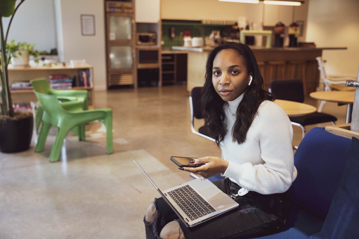Woman on Laptop with Phone and Earbuds