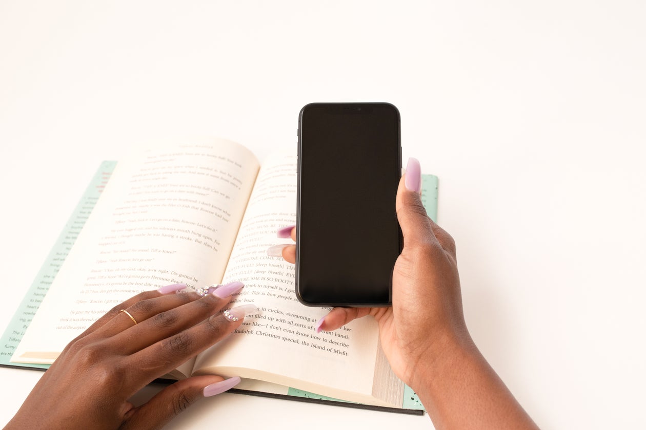Woman holding a phone while reading a book