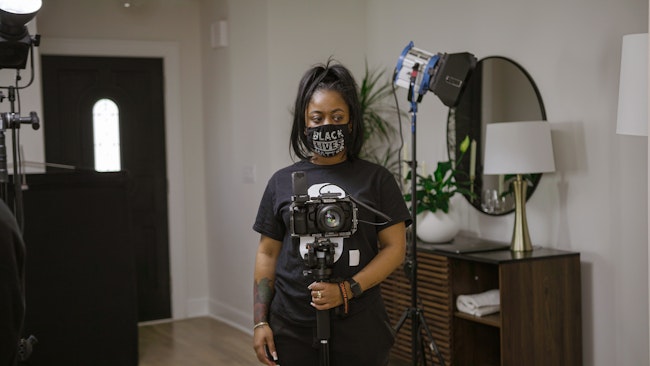 Black Woman holding a Camera with tripod