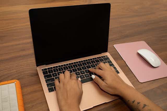 Hands typing on a laptop