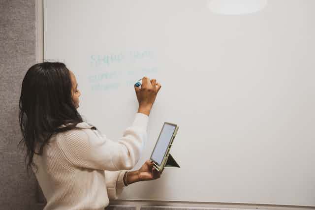 Woman in Conference Room With Tablet & Whiteboard