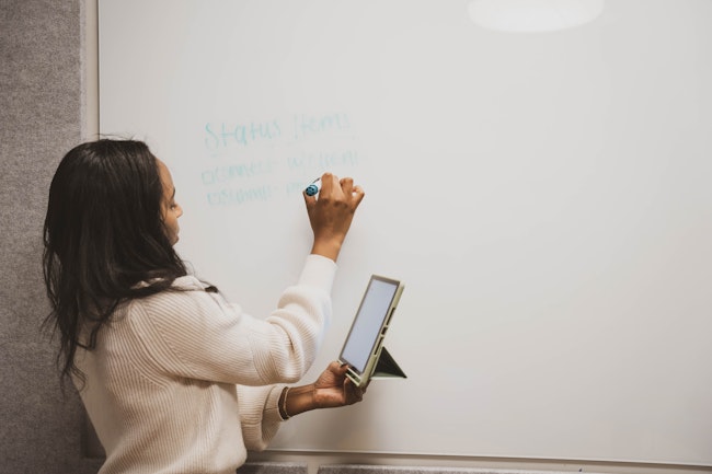 Woman in Conference Room With Tablet & Whiteboard