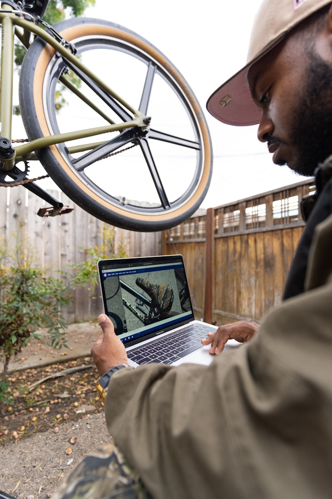 Man Conducts Bike Repairs with Laptop