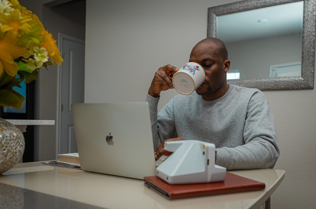 Man Sips Coffee at Desk