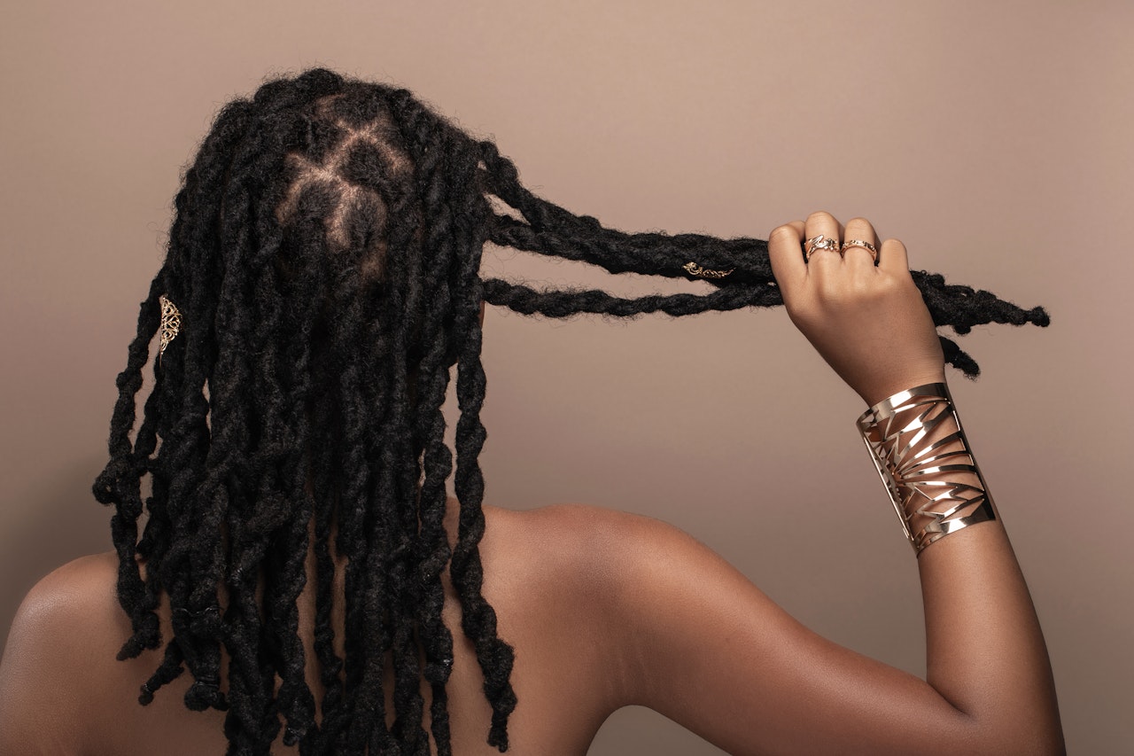 A brown skin person with locs pulls a handful of them to the right